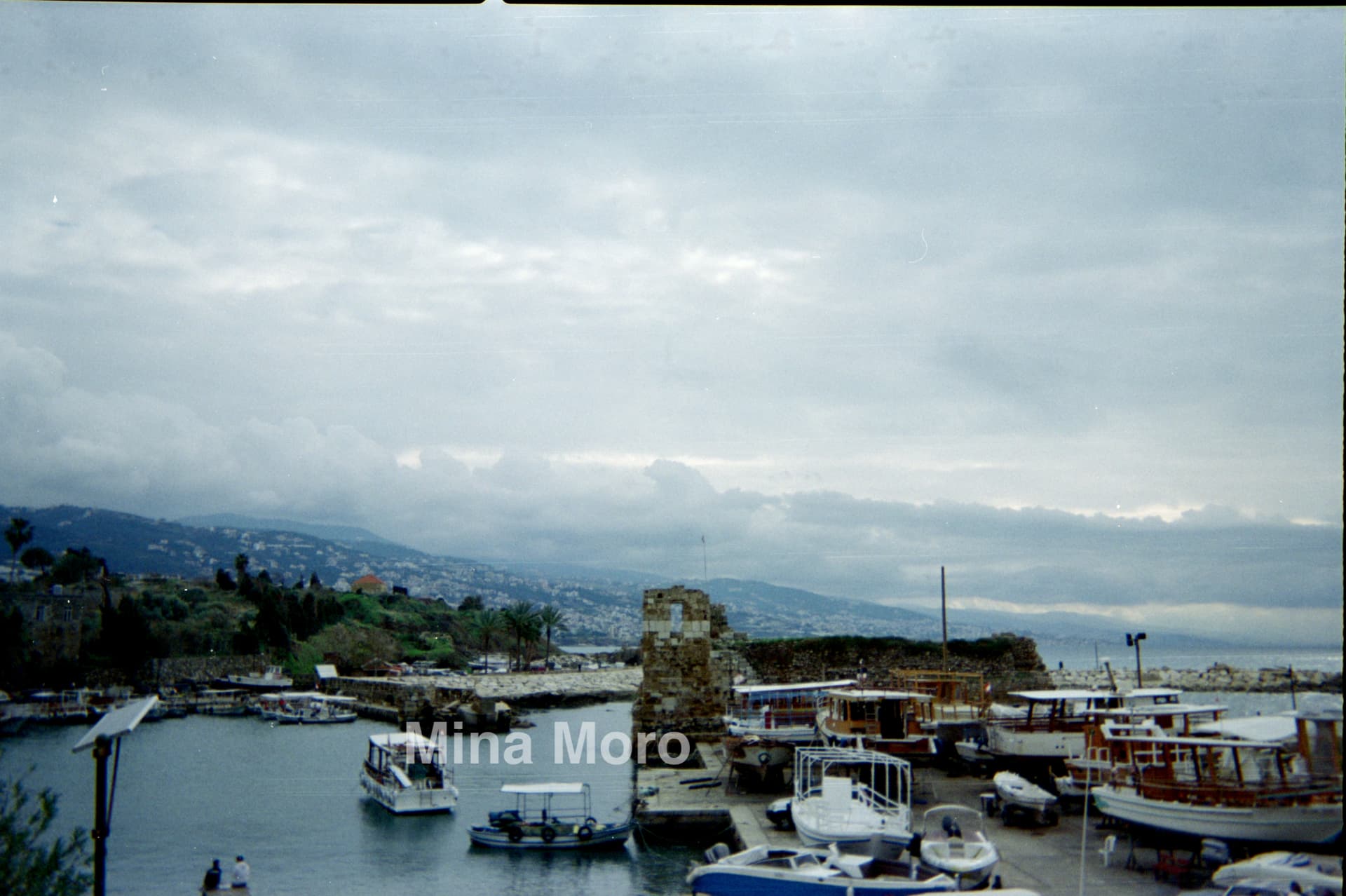 Fishing boats moored in the old harbour of Byblos, Lebanon, under a grey sky